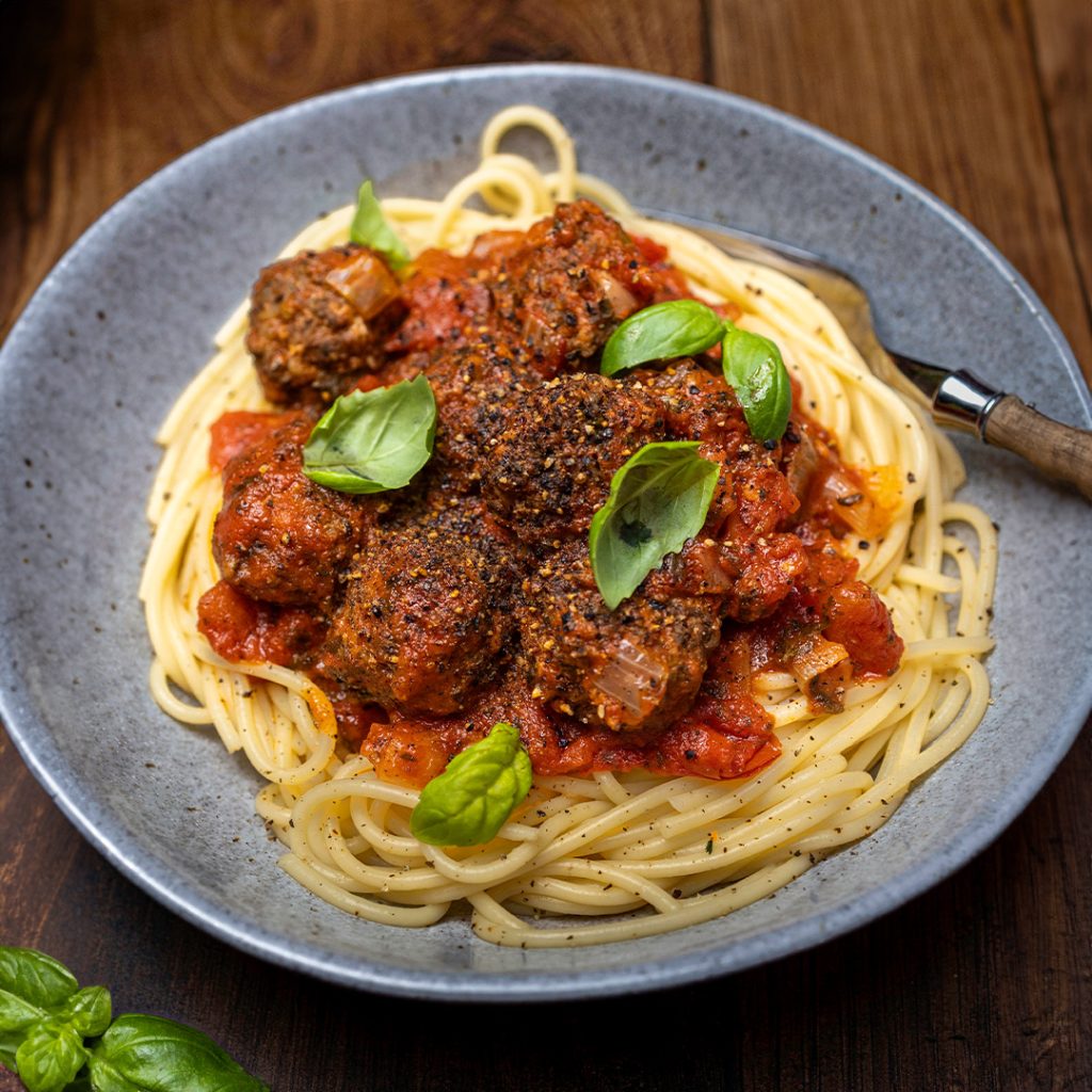 Plate of blackpudding meatballs and spaghetti with sauce and cutlery